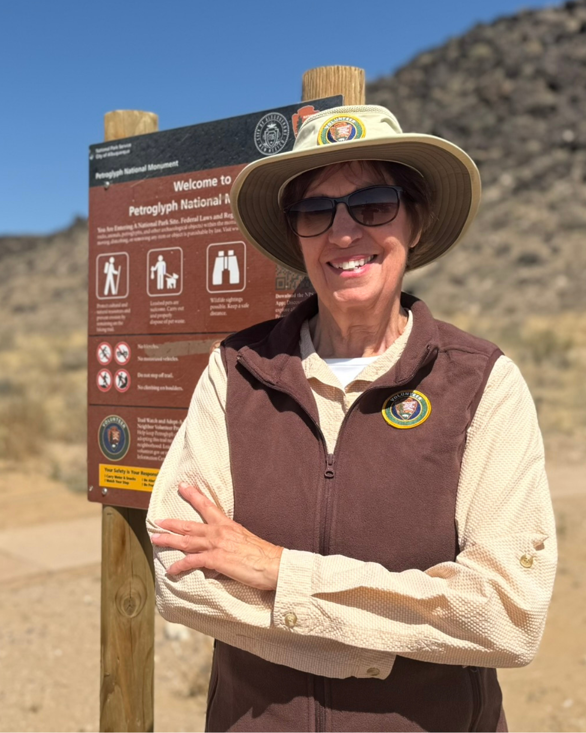 Picture of Albuquerque Open Space Volunteer Jan Powell standing next to a trail head sign