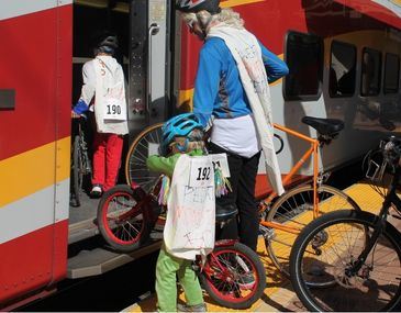 People dressed in costume loading bicycles onto the Rail Runner train
