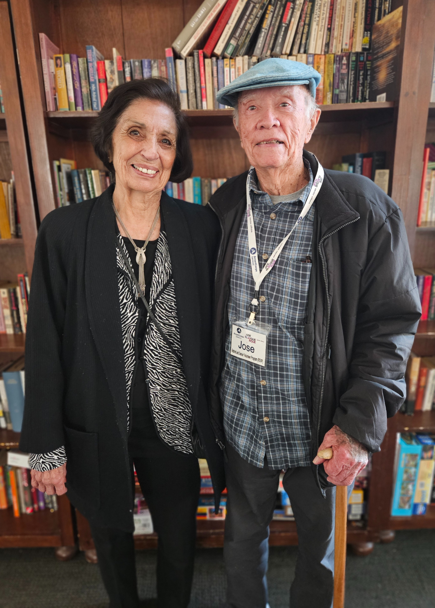 Picture of a man and a woman standing in front of library shelves and smiling at the camera