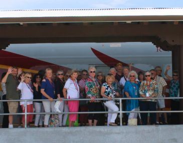 Group of seniors standing on the Rail Runner train platform waving at the camera
