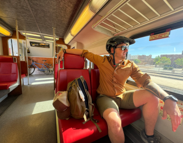 Picture of a man in a bicycle helmet sitting on a Rail Runner train seat
