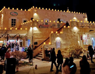 Picture of people shopping and mingling at night below holiday lights in Old Town Albuquerque 