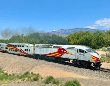 Picture of the Rail Runner train on a sunny day with the Sandia Mountains in the background