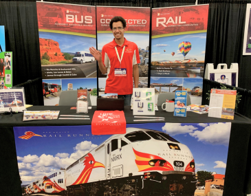 Rio Metro employee Eric Murphy standing behind an information booth for the Rail Runner