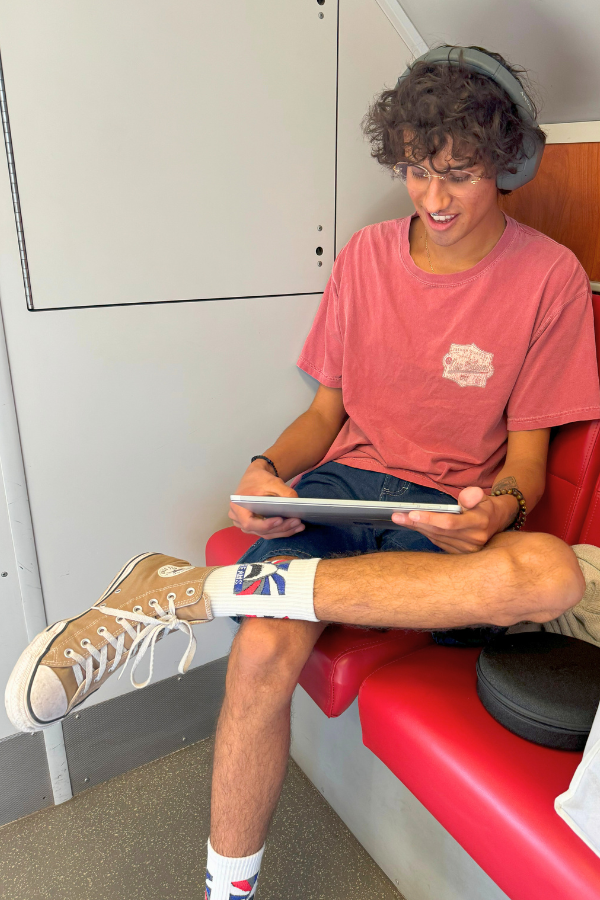 Young train commuter working on tablet wearing headphones October 2024 (1)