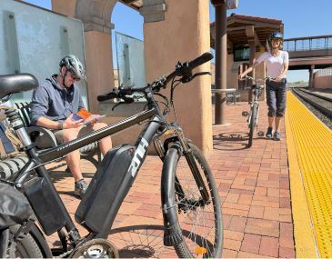 Picture of two people with bicycles waiting for the Rail Runner train at a station