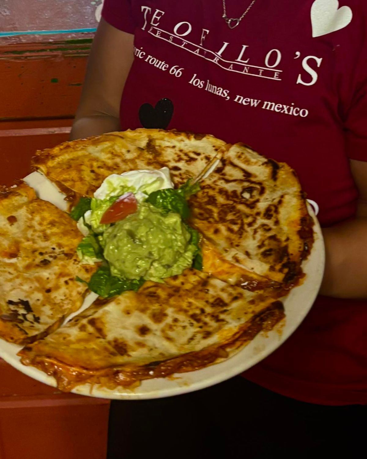 Picture of a woman holding a plate with a quesadilla at Teofilos Restaurant in New Mexico