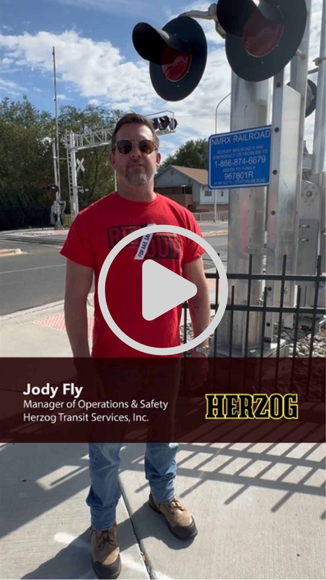 Picture of a transit safety professional next to a blue and white emergency railroad sign