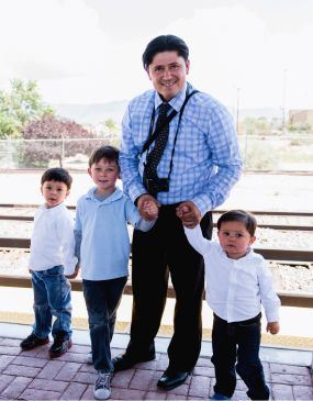 Man with Kids Holding Hands at a Rail Runner Station