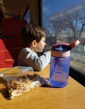 Young Child Riding the Rail Runner Train Sitting at Table with Snacks
